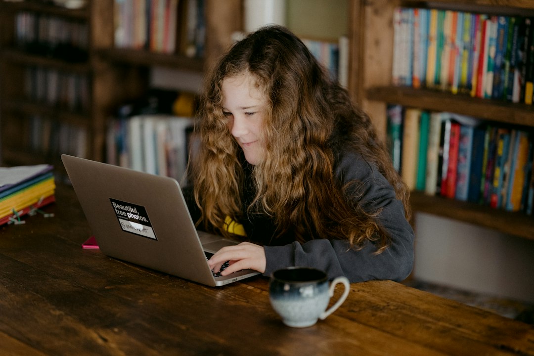 Teenager doing homework at a desk with a laptop and school materials