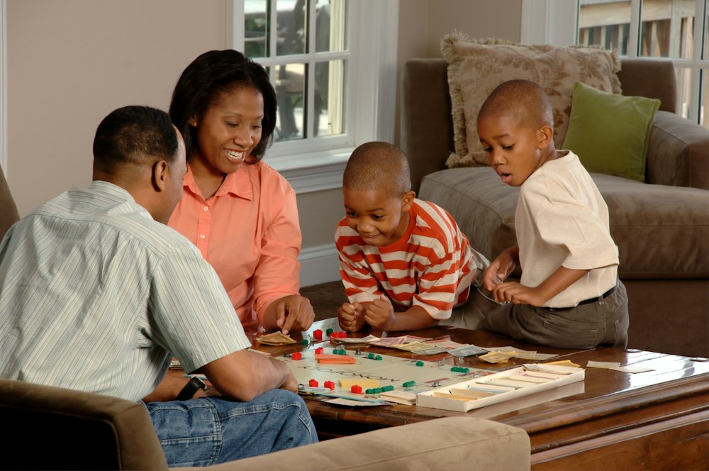Family members sitting around a coffee table playing a board game together