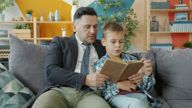 Father reading a book with his young son on a couch